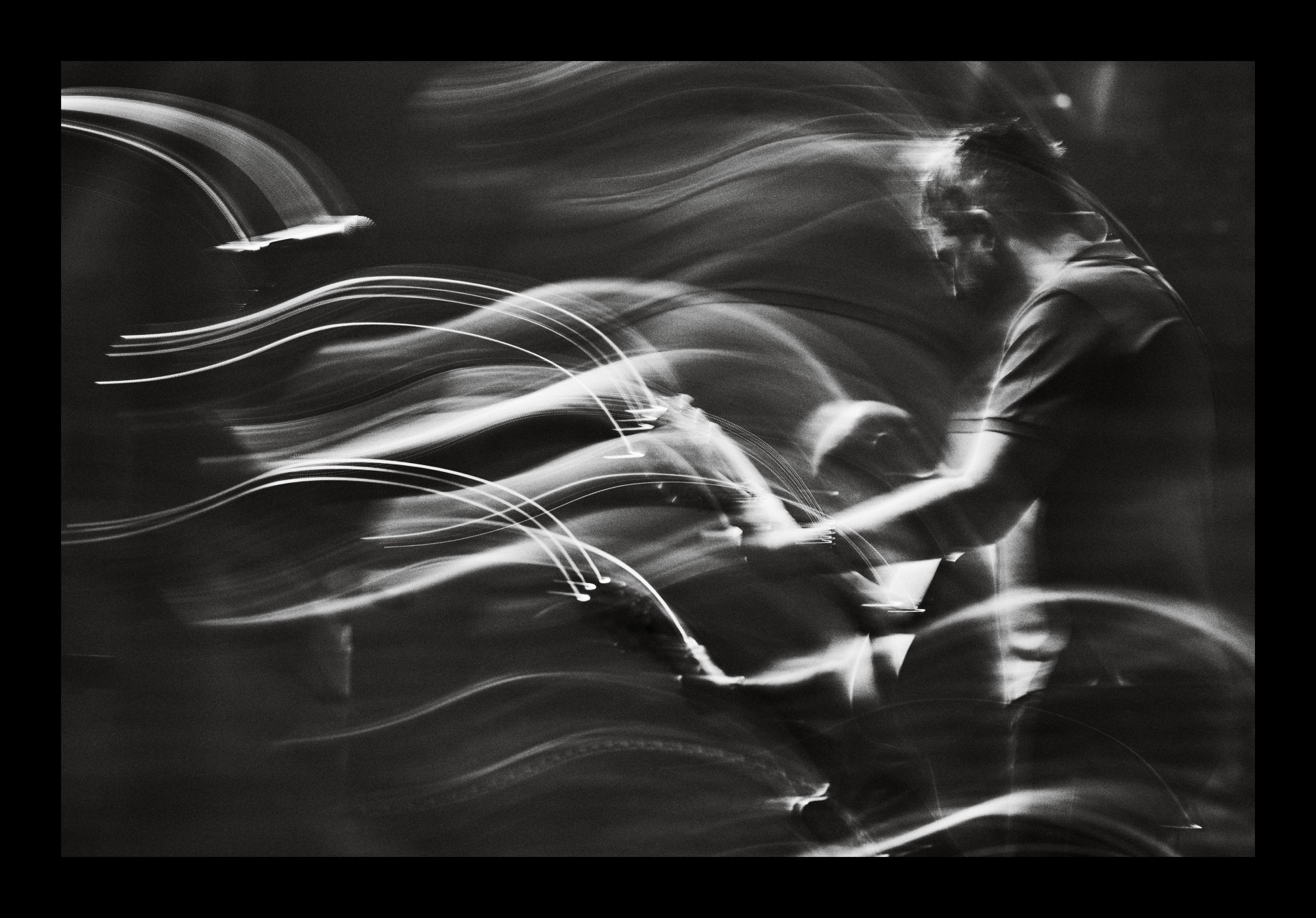 A black-and-white, long-exposure photo captures the singer in person, surrounded by high-energy light trails.