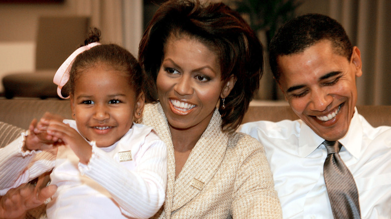 Sasha, Michelle and Barak Obama smile next to each other