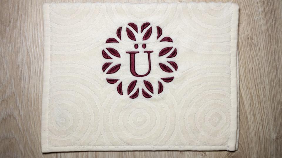 Decorative design, alphabet monogram E and Ü. Machine embroidery with burgundy colored cotton towel.