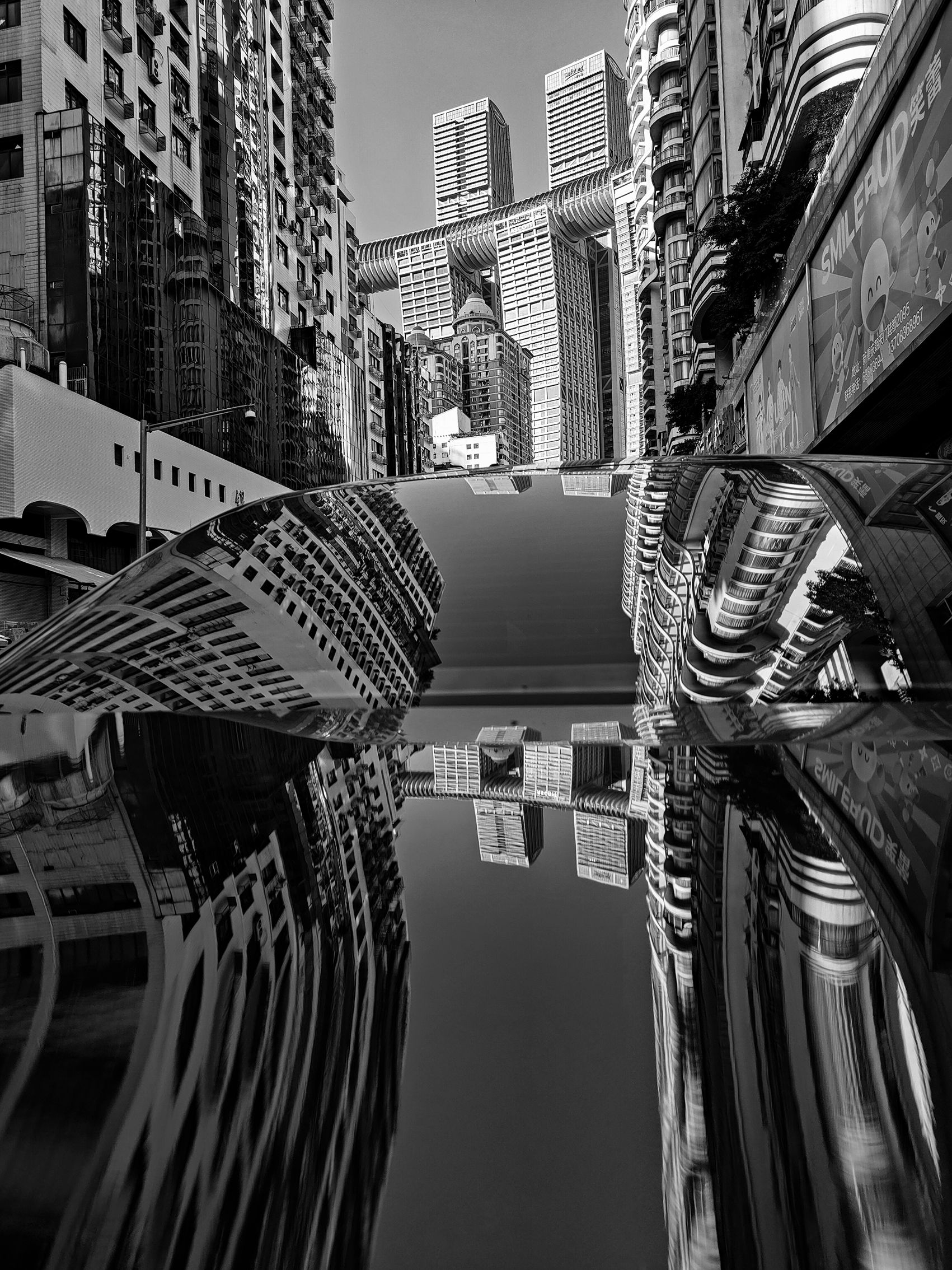 A black and white image of skyscrapers projected onto the roof of a car, creating a surreal, mirrored effect, with tall buildings lining the street.