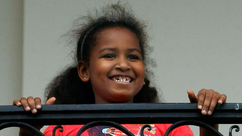 Sasha Obama smiles as she hangs on the balcony