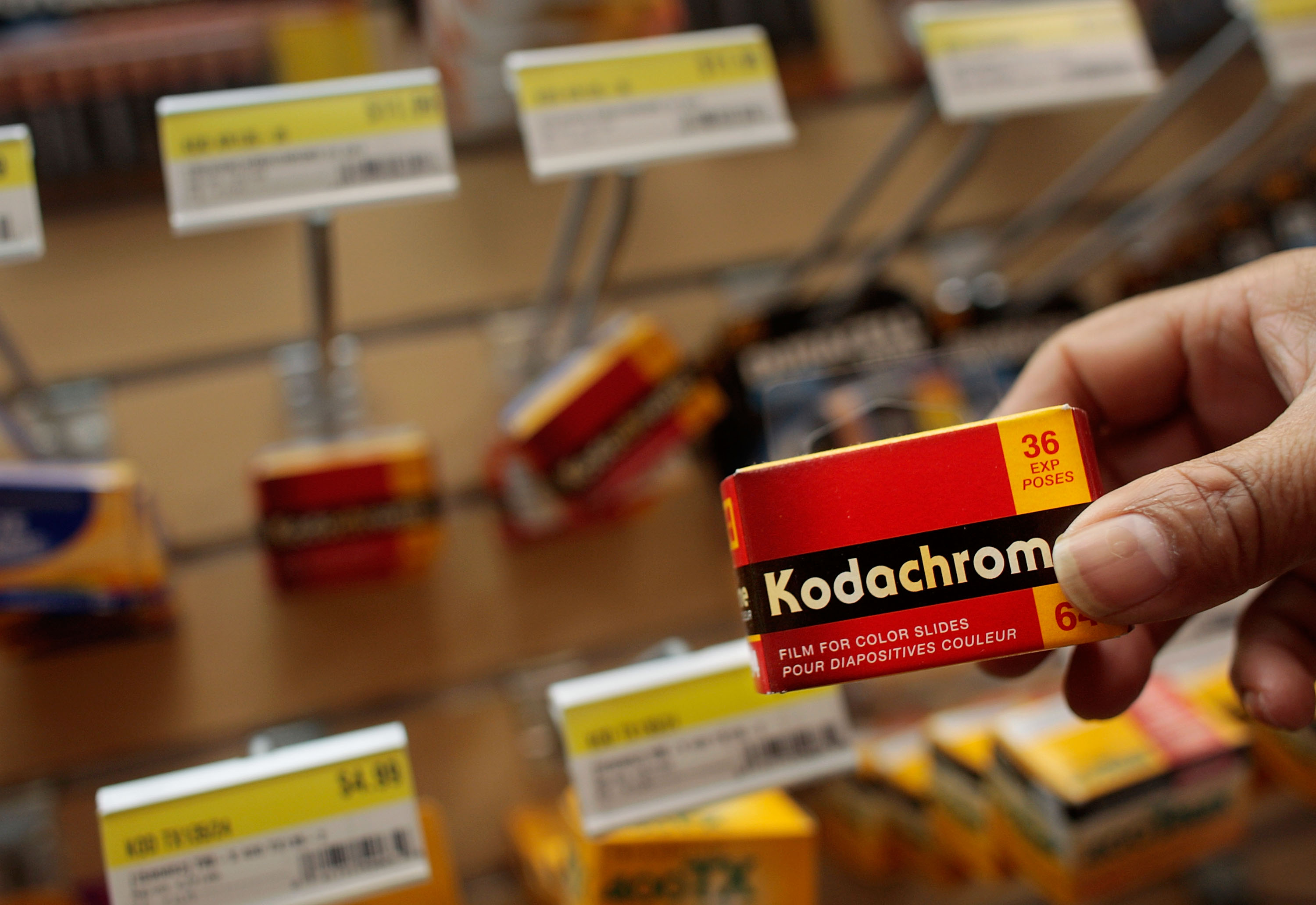 A box of Kodachrome film is held in the hand of a person in a camera shop