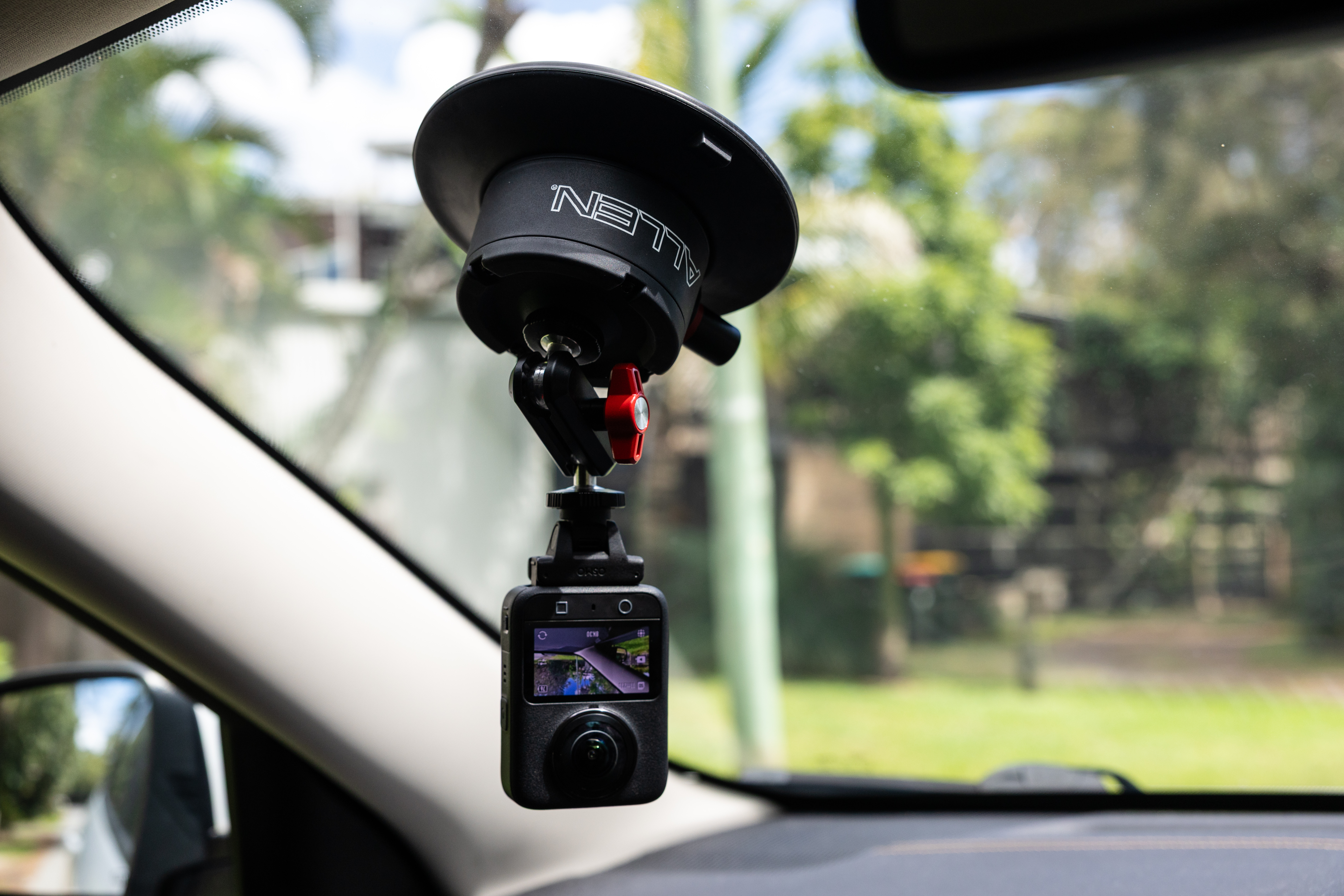 The Allen Smart Suction Snap Camera Mount is attached to the inside of the vehicle's windshield, holding the DJI action camera in a low position to record the vehicle.