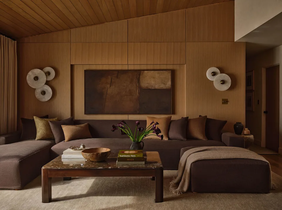 In the living room, a Galerie Solis Commune piece in Tobacco linen sets the tone, paired with a vintage 1980s stone coffee table from 1stDibs on a Lulu and Georgia rug. Nearby, asymmetrical iterations of Apparatus Studios' alabaster Median sconces cast a soft glow, and the niche above the sofa is framed by an original work from Rachel Mishael's Elemental series, commissioned by Solis.