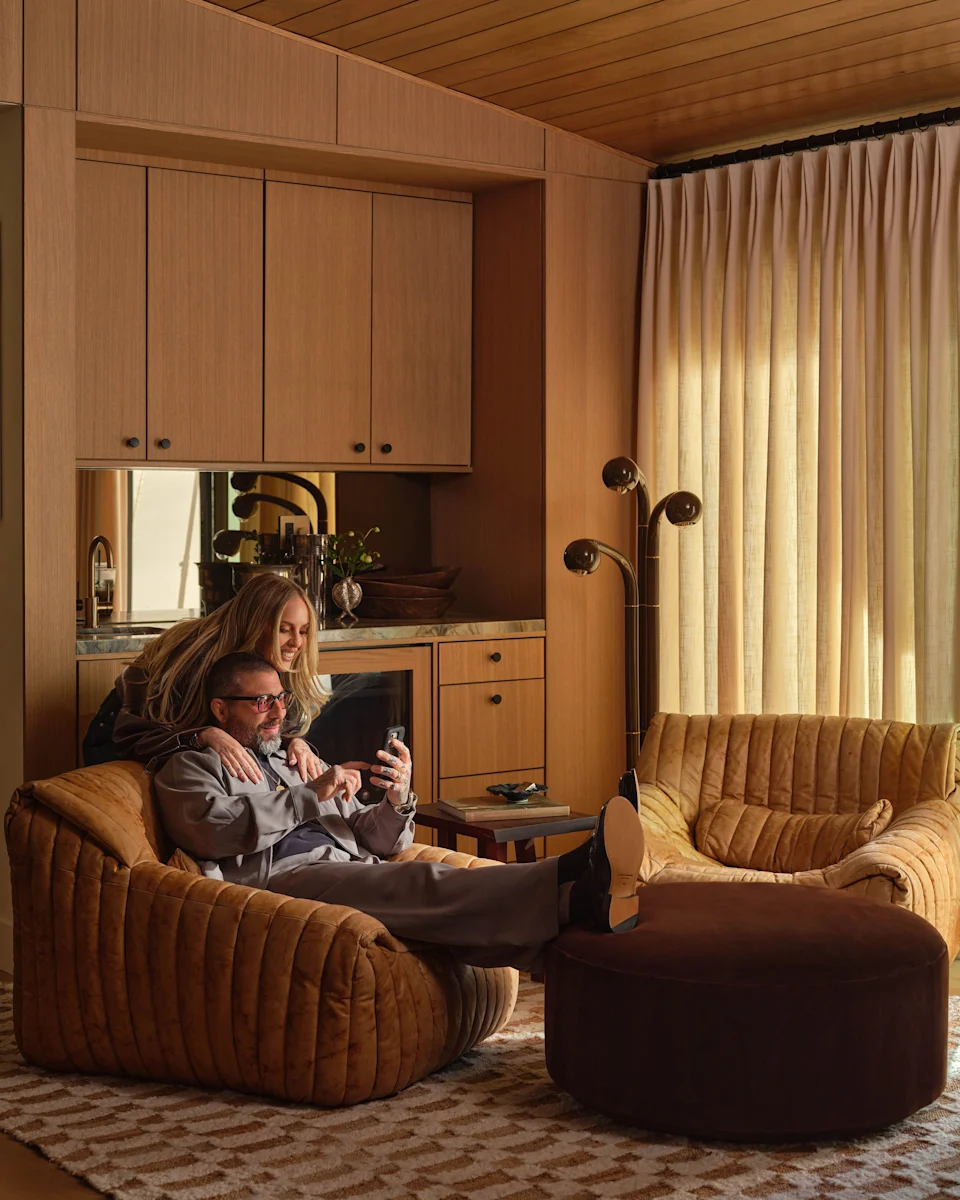 Entertainment areas, like the den, are clad in warm white oak. The sink has a green onyx countertop. Solis added vintage silverware and bowls from Olive Ateliers for a vintage feel. The side table is from Claude Home; rug is by Cappelen Dimyr.