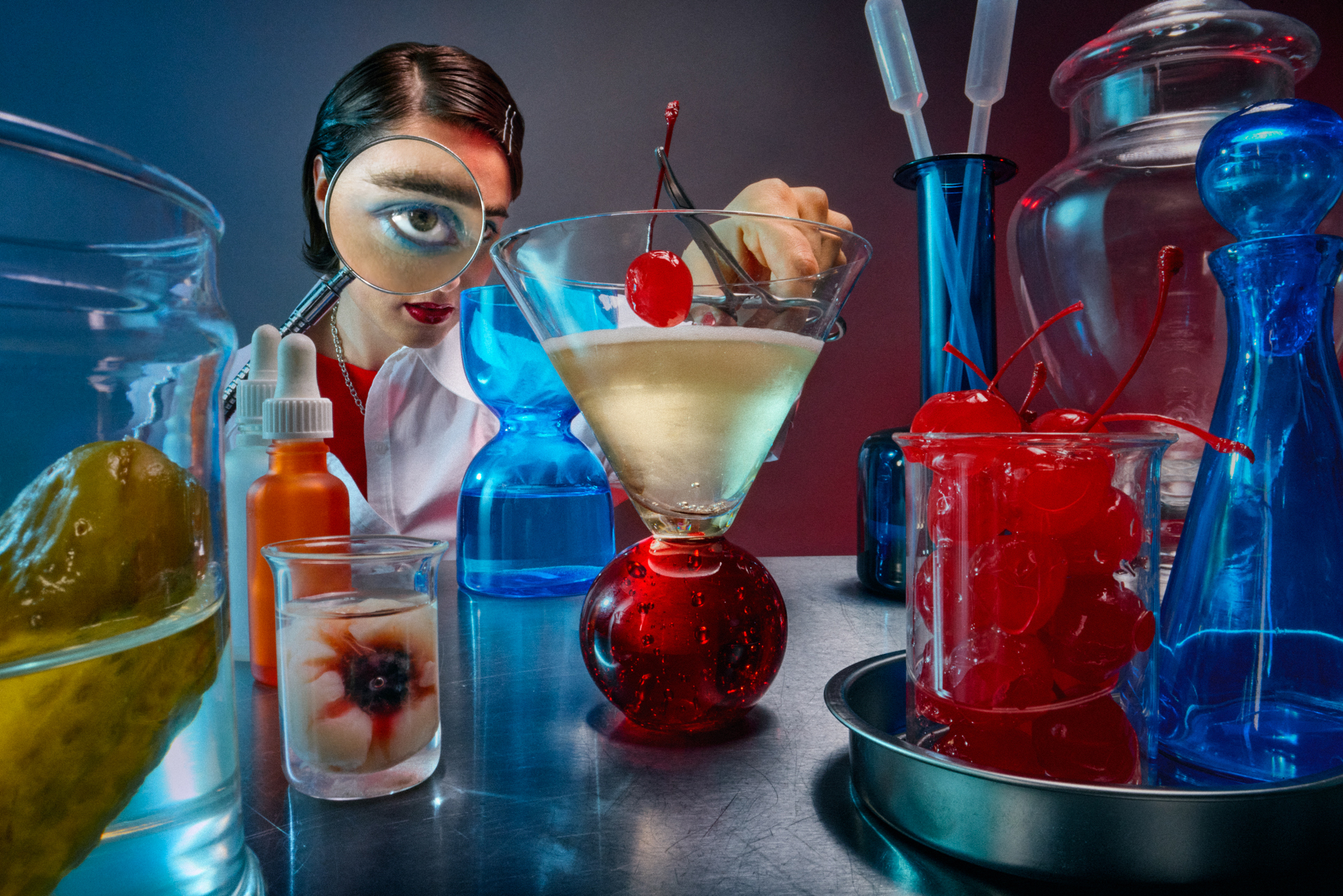 A man in a lab coat peers through a magnifying glass in a cherry-blossom shop, surrounded by colorful jars and glassware in a bright setting.