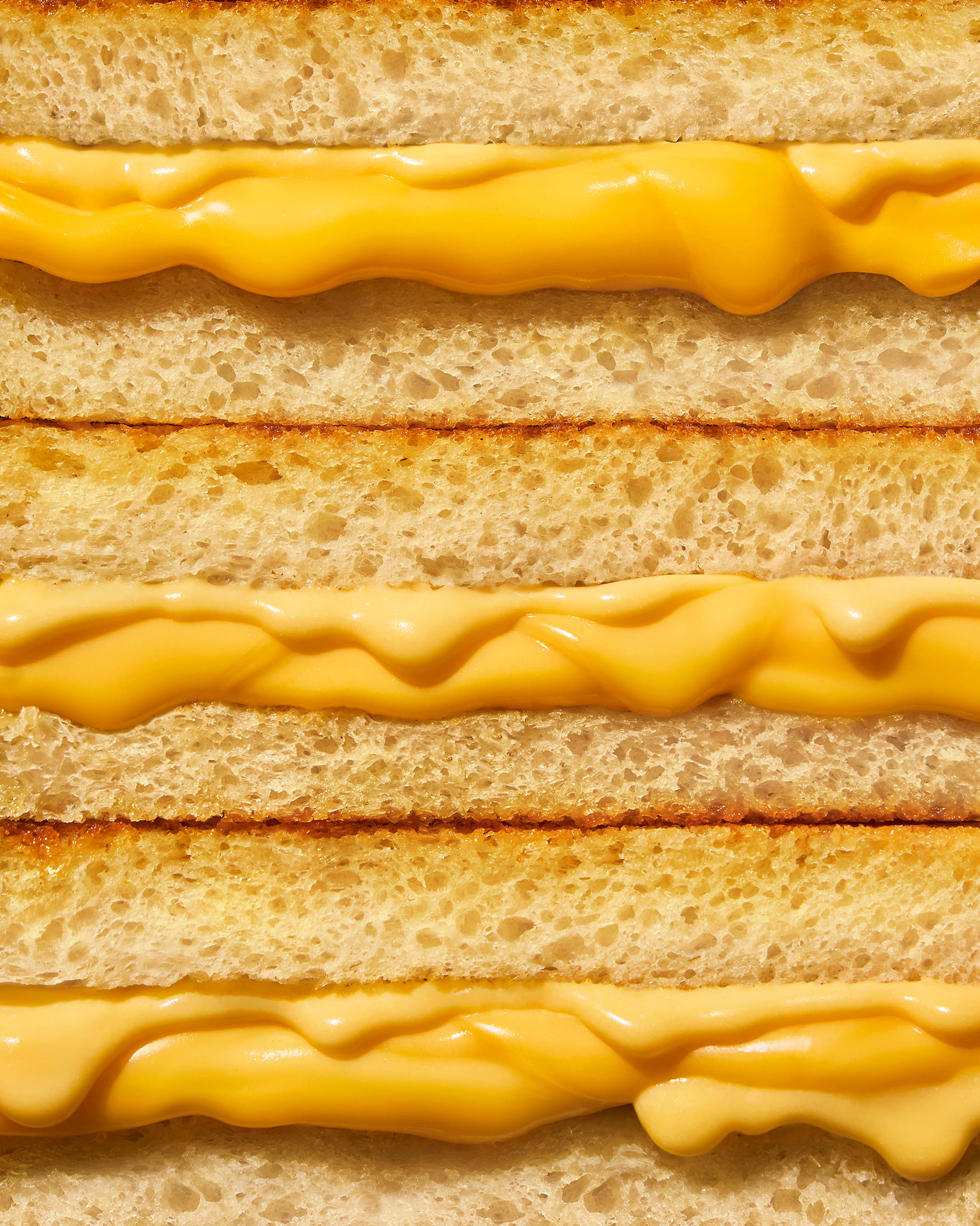 Next to it are three grilled cheese sandwiches in a row, with melted yellow cheese oozing between slices of toasted golden brown bread.