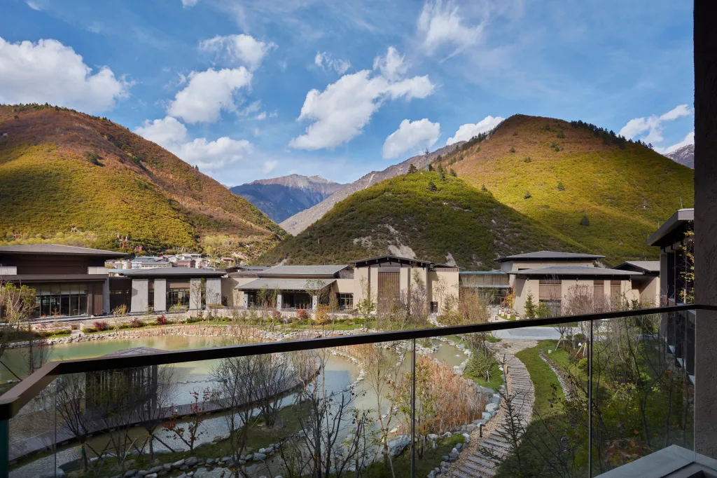 Modern buildings with glass windows, beautiful gardens, ponds with walkways and beautiful hills under blue skies.